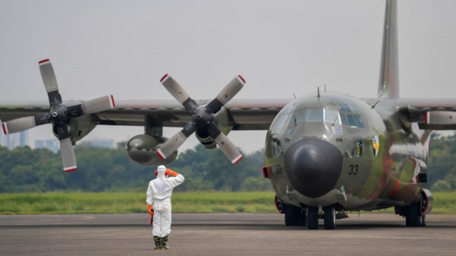 Prajurit TNI AU yang megenakan pakaian alat pelindung diri (APD) memberi hormat saat pesawat C-130 Hercules di Lanud Halim Perdanakusuma, Jakarta, Senin (23/3). Foto: ANTARA FOTO/M Risyal Hidayat