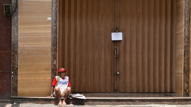 Seorang penjual koran beristirahat di depan toko yang tidak beroperasi di kawasan perdagangan Pasar Baru, Jakarta, Selasa (24/3/2020). Foto: ANTARA FOTO/Aditya Pradana Putra