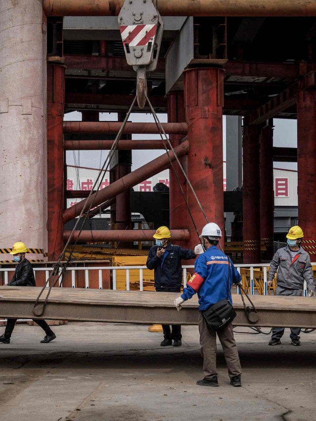 Pekerja di lokasi pembangunan jembatan di Wuhan mengenakan masker saat bekerja, Selasa (24/3). Foto: AFP/STR