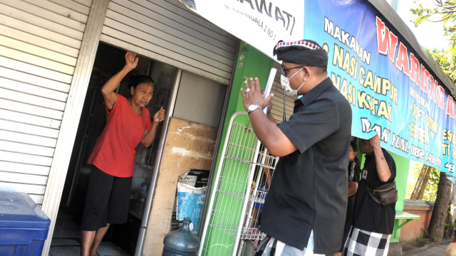 Pecalang atau petugas pengamanan adat Bali memberikan imbauan kepada masyarakat untuk menutup tempat usaha di wilayah Desa Adat Tuban, Badung, Bali. Foto: ANTARA FOTO/Fikri Yusuf