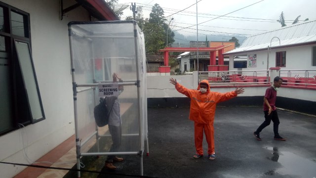 Warga Rembul yang baru tiba di kampung halaman disemprot disinfektan dalam Screening Room. (foto: bentar)