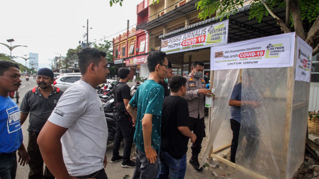 Warga keluar bilik disinfektan Posko Jurnalis Peliput Corona. Foto: ANTARA FOTO/Rahmad
