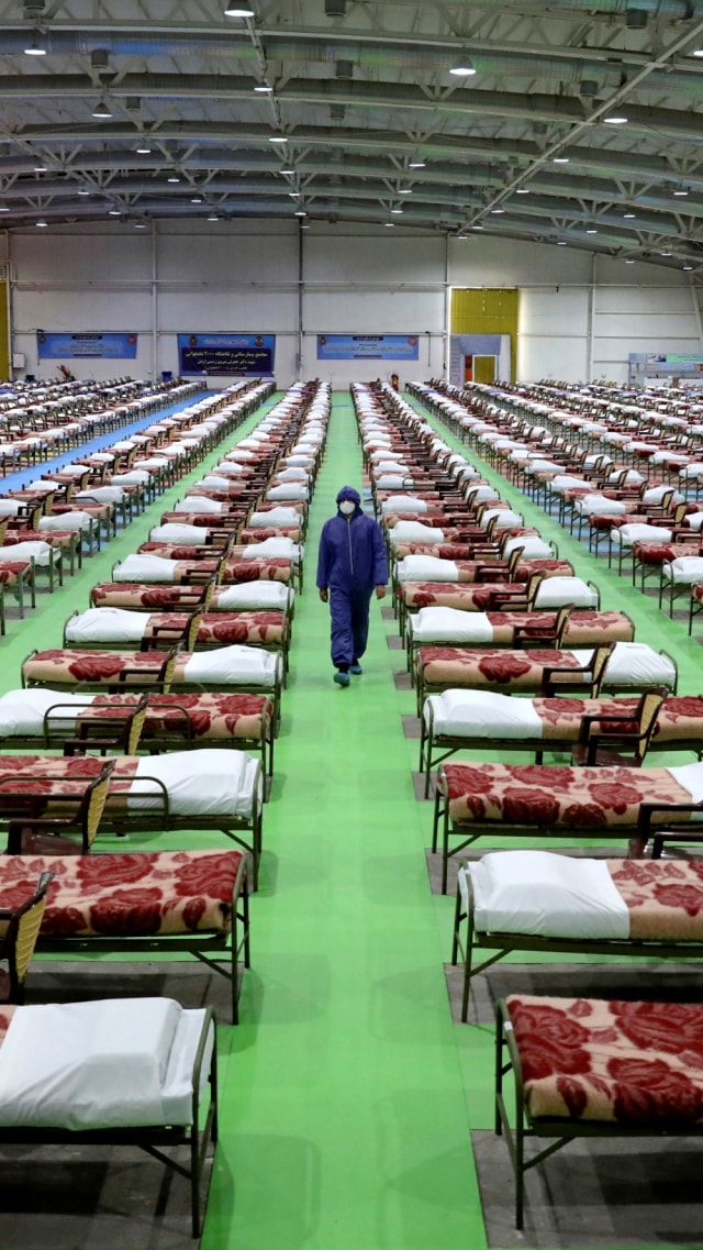 Seorang tentara Iran berjalan melewati barisan tempat tidur di rumah sakit sementara untuk pasien corona, di pusat pameran internasional di Teheran Utara, Iran. Foto: AP Photo/Ebrahim Noroozi