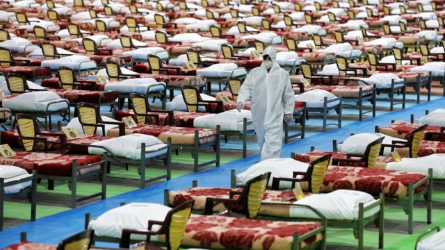Seorang petugas mengenakan baju hamzat di rumah sakit sementara untuk pasien corona, di pusat pameran internasional di Teheran Utara, Iran. Foto: AP Photo/Ebrahim Noroozi