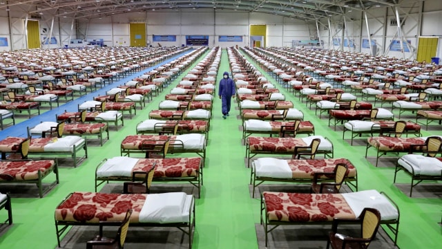 Seorang tentara Iran berjalan melewati barisan tempat tidur di rumah sakit sementara untuk pasien corona, di pusat pameran internasional di Teheran Utara, Iran. Foto: AP Photo/Ebrahim Noroozi