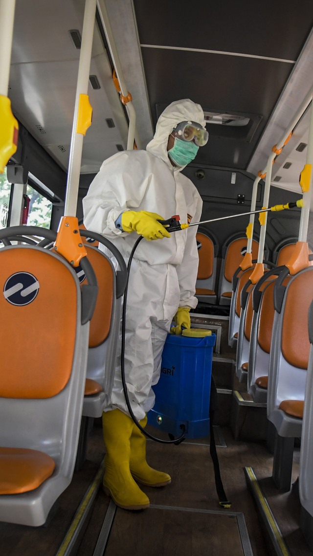 Petugas menyemprotkan cairan disinfektan pada bus Transjakarta untuk petugas medis yang menginap di Hotel Grand Cempaka Bisnis, Jakarta, Sabtu (28/3/2020).  Foto: Antara/Galih Pradipta