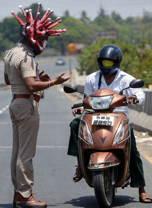 Rajesh Babu, seorang polisi mengenakan helm berbentuk virus corona meminta masyarakat untuk tinggal di rumah selama wabah COVID-19 di Chennai, India. Foto: Reuters/P. Ravikumar