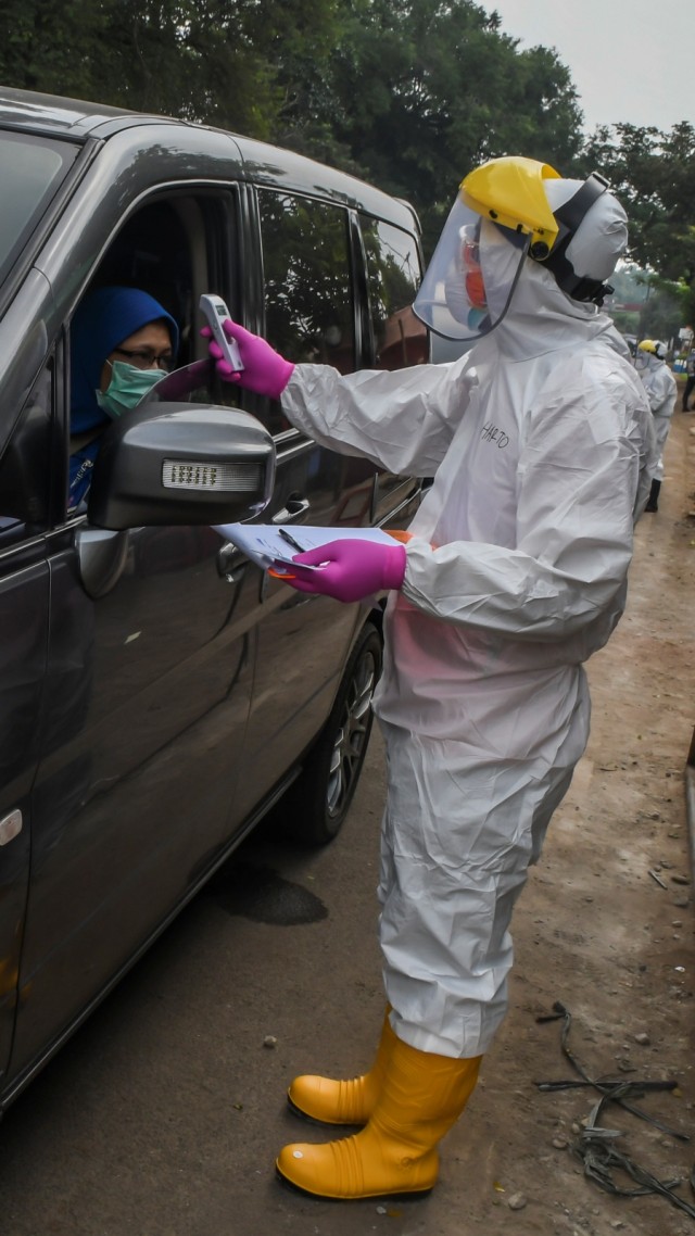 Petugas Dinas Kesehatan Kota Depok memeriksa suhu pengendara saat melakukan pengecekan COVID-19 dengan sistem "drive thru" di Cimanggis, Depok, Minggu (29/3). Foto: ANTARA FOTO/Muhammad Adimaja