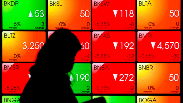 Pekerja melintas di depan layar yang menampilkan informasi pergerakan harga saham di gedung Bursa Efek Indonesia (BEI), Jakarta, Selasa (31/3) Foto: ANTARA FOTO/Muhammad Adimaja