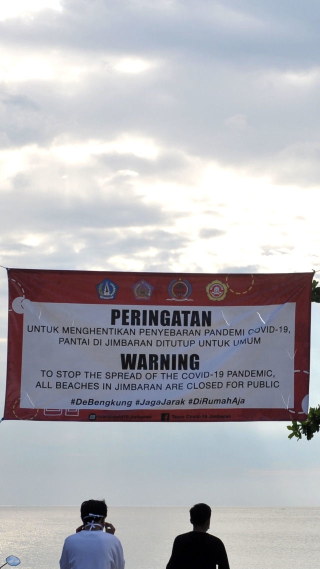 Spanduk penutupan kawasan sementara terpasang di kawasan wisata Pantai Jimbaran, Badung, Bali. Foto: ANTARA FOTO/Fikri Yusuf
