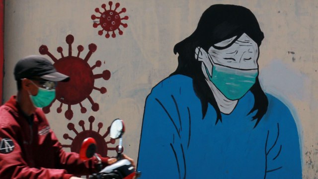 Pengendara motor melintas di depan mural tentang pandemi virus corona atau COVID-19 yang ada di Selapajang, Tangerang, Banten. Foto: ANTARA FOTO/Muhammad Iqbal