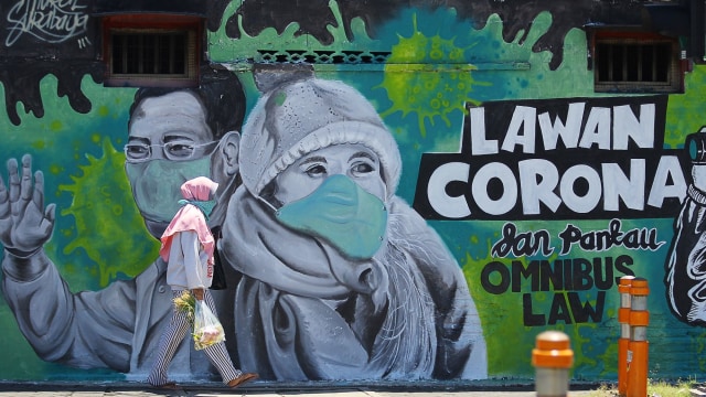 Warga melintas di depan mural Lawan Corona di Surabaya. Foto: ANTARA/Moch Asim