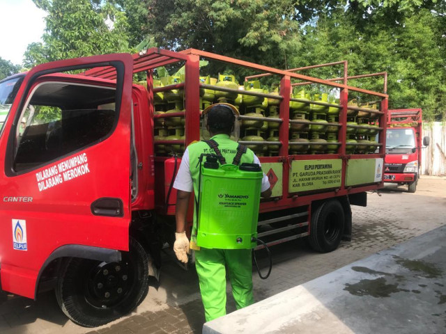 Petugas sedang menyemprotkan desifektan ke truk distribusi Gas LPG. Foto: Erfanto