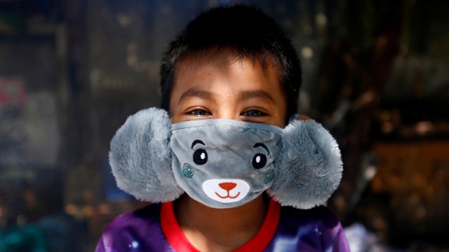 Panji (8), mengenakan masker wajah berbentuk binatang sambil berjemur matahari pagi di tengah penyebaran penyakit virus corona. Foto: REUTERS / Ajeng Dinar Ulfiana