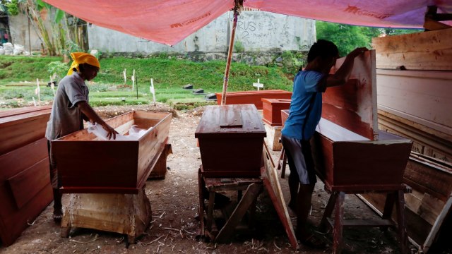 Suherman (45) dan Ari Rusmawan (32) menyiapkan peti mati yang akan disumbangkan di TPU Pondok Kelapa, Jakarta Timur, Rabu (8/4). Foto: REUTERS/Willy Kurniawan