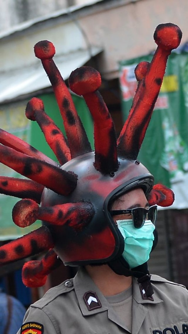 Anggota polisi lalu lintas Polres Mojokerto melakukan sosialisasi penggunaan masker dengan memakai helm virus corona di pasar tradisional Sawahan, Jawa Timur. Foto: ANTARA FOFO/Syaiful Arif