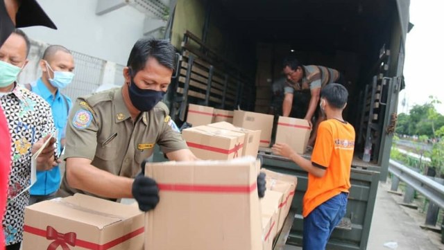 Petugas menurunkan bantuan sosial dari Pemprov DKI untuk diberikan kepada warga selama periode Penerapan Pembatasan Sosial Berskala Besar (PSBB) di DKI Jakarta. Foto: Instagram/@dkijakarta