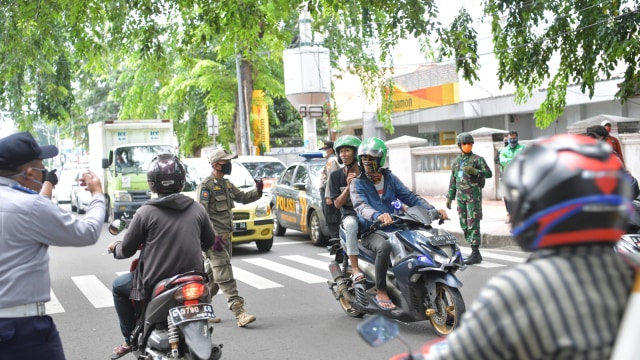 Petugas melakukan imbauan kepada pengendara motor untuk dapat mematuhi penerapan PSBB di jalan cempaka putih raya, Cempaka Putih, Jakarta (11/4). Foto: ANTARA FOTO/Nova Wahyudi