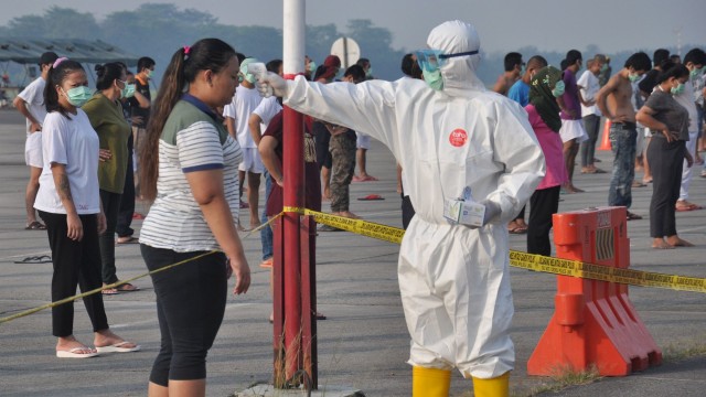 Petugas medis Gugus Tugas Percepatan Penanganan COVID-19 Sumut memeriksa suhu tubuh seorang Tenaga Kerja Indonesia (TKI) asal Malaysia. Foto: ANTARA FOTO/Septianda Perdana