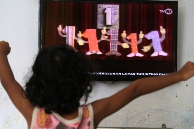 Seorang anak menonton televisi siaran perdana 'Belajar dari Rumah' melaui siaran TVRI di rumah mereka, di Kota Kediri, Jawa Timur, Senin (13/4). Foto: ANTARA FOTO/Prasetia Fauzani