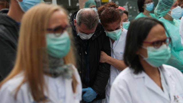 Petugas kesehatan menghadiri penghormatan untuk rekan kerja mereka Esteban yang meninggal karena virus corona di RS Severo Ochoa di Spanyol (14/4). Foto: REUTERS / Susana Vera