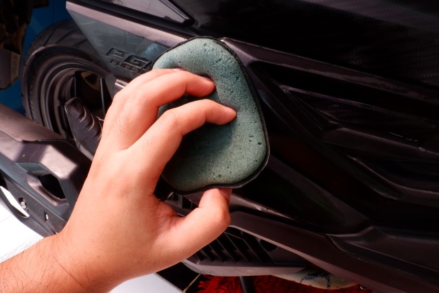 Pengaplikasian busa aplicator pad yang sudah diberi cairan trim restorer ke bodi plastik motor Foto: Aditya Pratama Niagara/kumparan