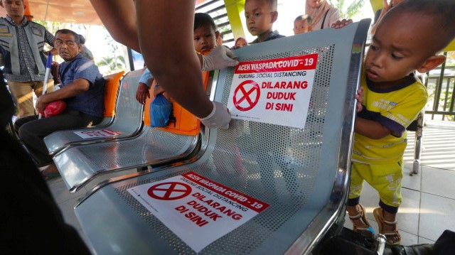 Seorang petugas menempelkan stiker untuk menjaga jarak selama masa pandemi Virus Corona. Foto: kumparan 