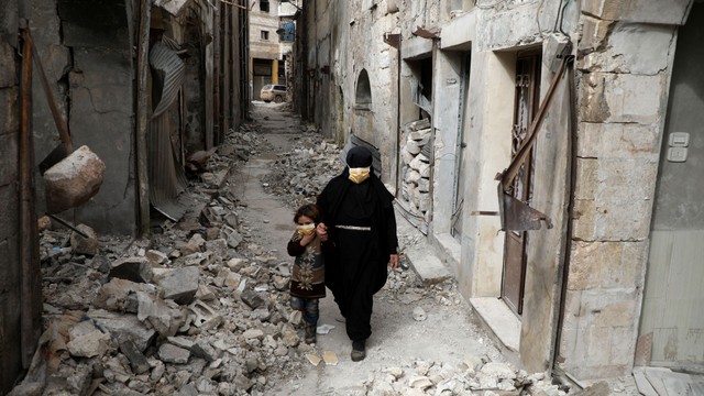 Warga Suriah melintasi reruntuhan bangunan, di kota Ariha di pedesaan selatan provinsi Idlib, Suriah, 11 April 2020. Foto: AFP/AAREF WATAD