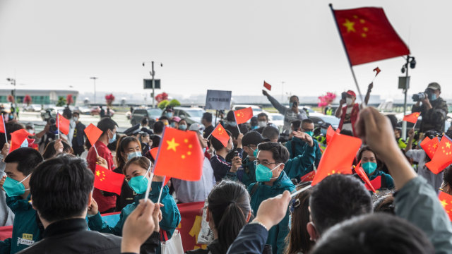 Sejumlah relawan memberikan isyarat kepada staf medis dari Medical College Peking Union  di Bandara Internasional Tianhe, Wuhan, China. Foto: AFP/STR