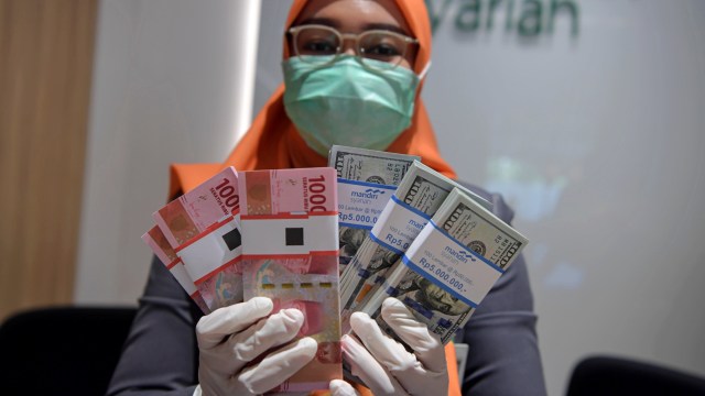 Karyawan menghitung uang rupiah dan dolar AS di Bank Mandiri Syariah, Jakarta, Senin (20/4/2020). Foto: ANTARA FOTO/Nova Wahyudi
