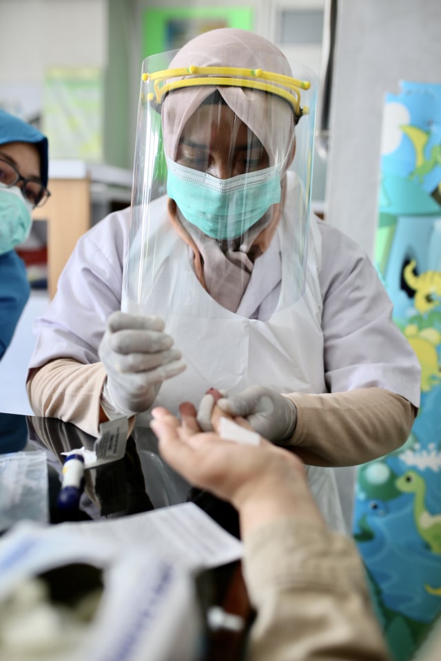 Petugas kesehatan mengambil sampel darah dengan rapid test di Puskesmas Kopelma Darussalam, Banda Aceh, Senin (20/4). Foto: Abdul Hadi/acehkini