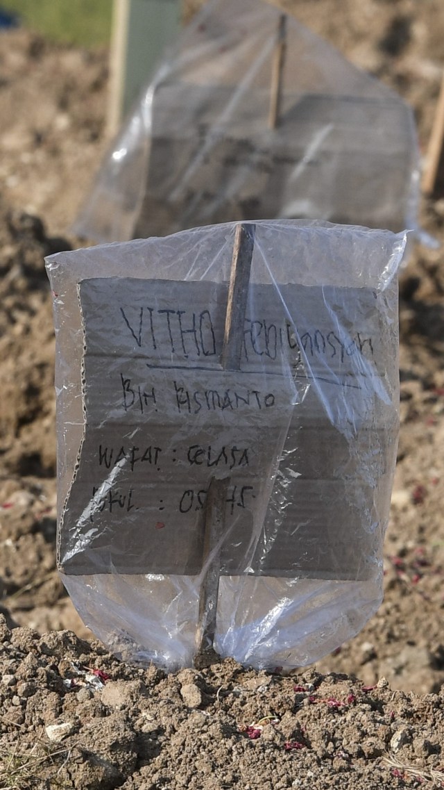 Sejumlah tanda pengenal yang terbuat dari kardus berada di pusara kasus meninggal akibat COVID-19 sebagai pengganti nisan di komplek TPU Tegal Alur, Jakarta. Foto: ANTARA FOTO/Muhammad Adimaja