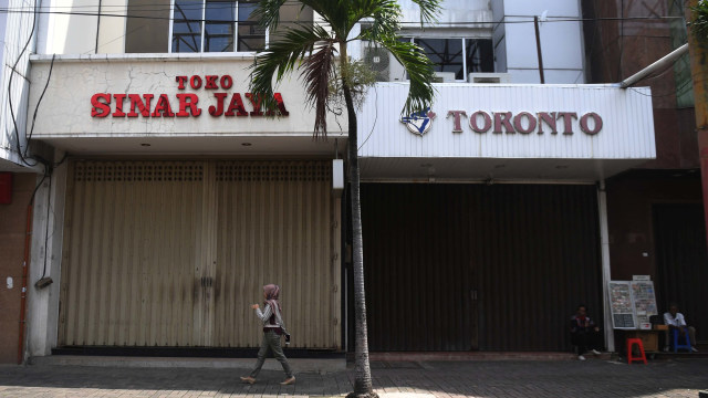 Seorang wanita melintasi deretan toko yang tutup di Pasar Baru, Jakarta. Foto: ANTARA FOTO / Akbar Nugroho Gumay