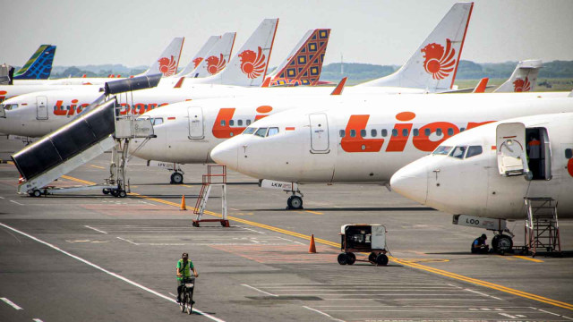 Petugas melintas di sejumlah peswat yang terparkir di Terminal 1 Bandar Udara Internasional Juanda, Sidoarjo, Jawa Timur, Sabtu (25/4/2020). Foto: Antara/Umarul Faruq
