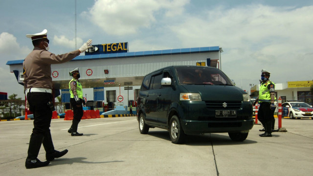 Petugas kepolisian menghentikan kendaraan saat penyekatan di pintu keluar tol Adiwerna, Kabupaten Tegal, Jawa Tengah. Foto: ANTARA FOTO/Oky Lukmansyah