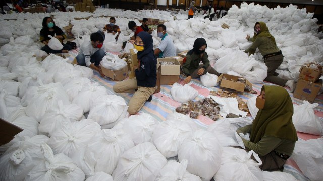 Relawan membungkus paket sembako bantuan dari berbagai perusahaan di Convention Hall, Surabaya, Jawa Timur, Minggu (26/4/2020). Foto: ANTARA FOTO/Moch Asim