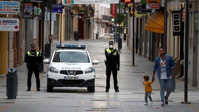 Petugas kepolisian setempat mengheningkan cipta tiga menit kesunyian untuk mengenang orang yang meninggal karena virus corona di Ronda, Spanyol. Foto: REUTERS/Jon Nazca