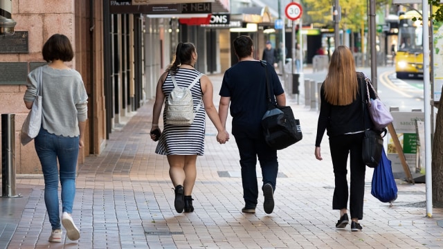 Warga berjalan pada hari pertama pencabutan lockdown di Wellington, Selandia Baru, Selasa (28/4). Foto: Marty MELVILLE/AFP