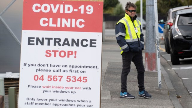 Seorang penjaga keamanan berdiri di luar klinik virus corona di Lower Hutt, dekat Wellington, Selandia Baru. Foto: Marty MELVILLE / AFP