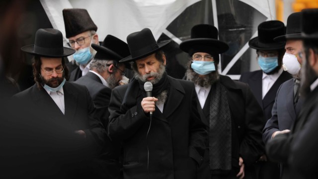 Anggota komunitas Yahudi Ortodoks mengenakan masker saat menghadiri pemakaman seorang rabi yang meninggal karena virus corona di Borough Park, Brooklyn. Foto: Getty Images/Spencer Platt
