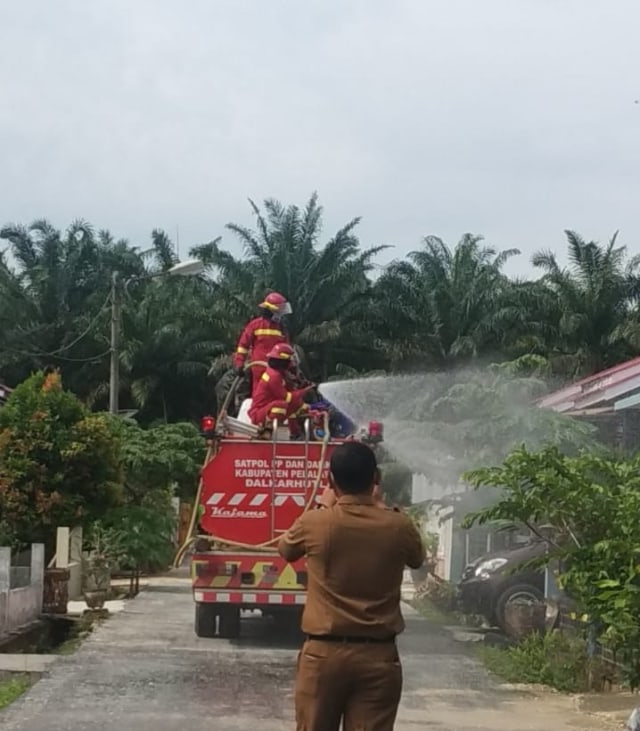 PETUGAS saat menyemprotkan cairan disinfektan ke rumah Dokter AS dan warga satu perumahan dengan sang dokter, beberapa waktu lalu. Dokter AS dinyatakan sembuh oleh dokter merawatnya di RSUD Pangkalan Kerinci, Pelalawan, Riau. 
