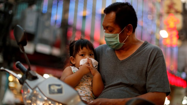 Seorang pria menggunakan masker menunggu makanan di  Chinatown, Bangkok, Thailand. Foto: REUTERS / Jorge Silva