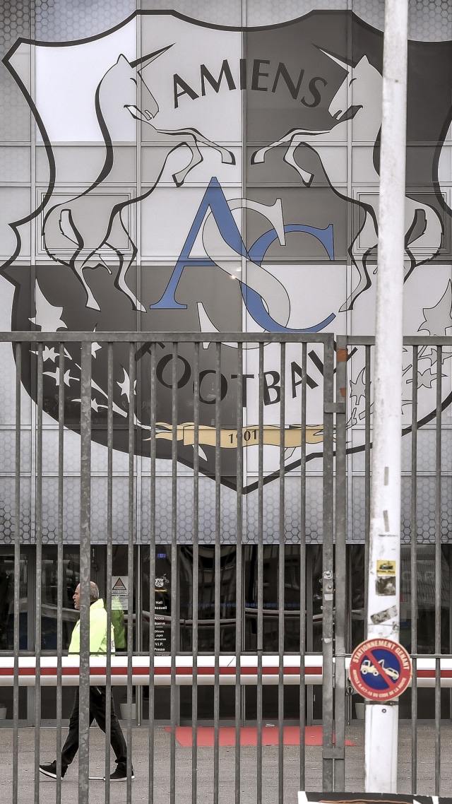 Seorang berjalan di pintu masuk Stade de la Licorne dengan logo klub sepak bola Amiens SC di Amiens, Prancis utara. Foto: AFP/PHILIPPE HUGUEN