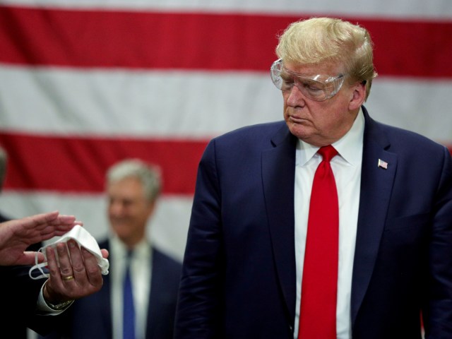Presiden AS Donald Trump melihat masker dari hasil produksi pabrik masker di Phoenix, Arizona, AS. Foto: REUTERS/Tom Brenner