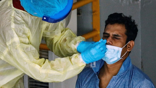Petugas medis melakukan test swab pada seorang pekerja migran di Singapura. Foto:  REUTERS / Edgar Su
