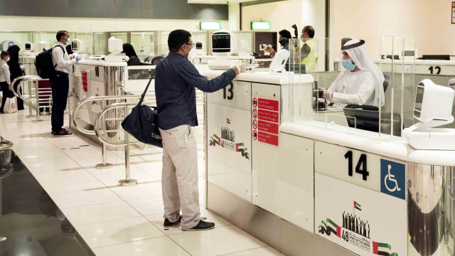 Warga Negara India mengunakan masker berdiri dalam antrian chek-in saat penerbangan pertama dari Dubai ke India di Bandara Internasional Dubai, UEA. Foto: Bandara Internasional Dubai / via REUTERS