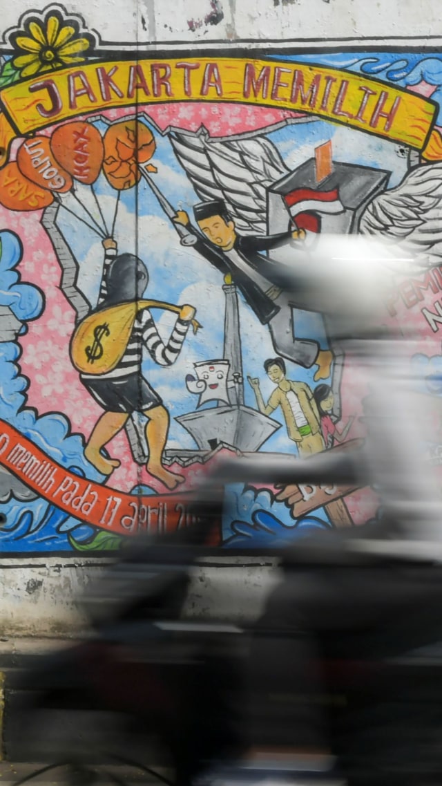 Warga melintas di depan mural bertema pemilihan umum di kawasan Dukuh Atas, Jakarta. Foto:  ANTARA FOTO/Galih Pradipta