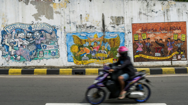 Warga melintas di depan mural bertema pemilihan umum di kawasan Dukuh Atas, Jakarta. Foto:  ANTARA FOTO/Galih Pradipta