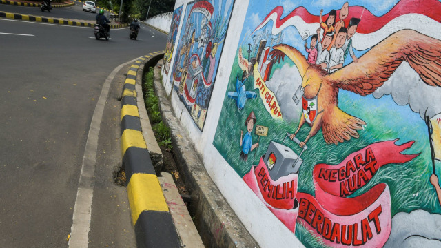Warga melintas di depan mural bertema pemilihan umum di kawasan Dukuh Atas, Jakarta. Foto:  ANTARA FOTO/Galih Pradipta