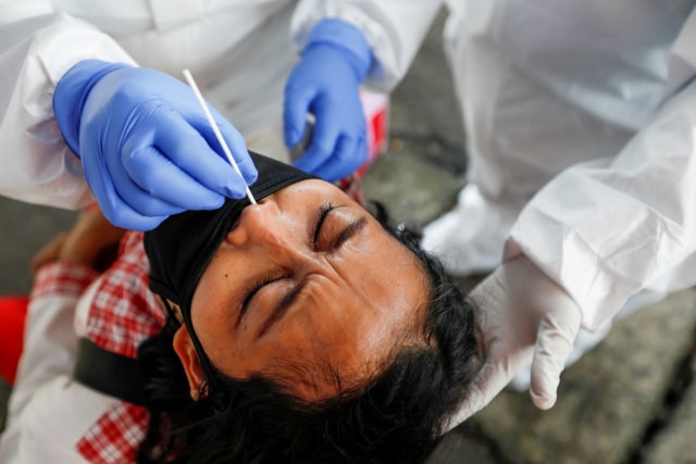 Petugas medis mengambil sampel cairan dari hidung dan tenggorokan warga saat mengikuti tes swab di pasar tradisional di Bogor, Jumat (8/5). Foto: REUTERS / Willy Kurniawan